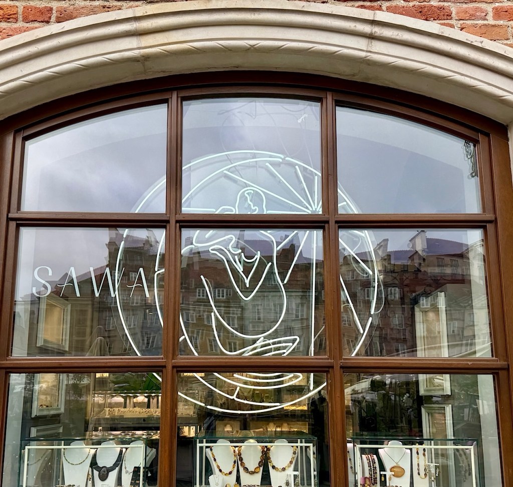 Storefront window displaying the name 'SAWA' with a decorative neon sign and jewelry on display.
